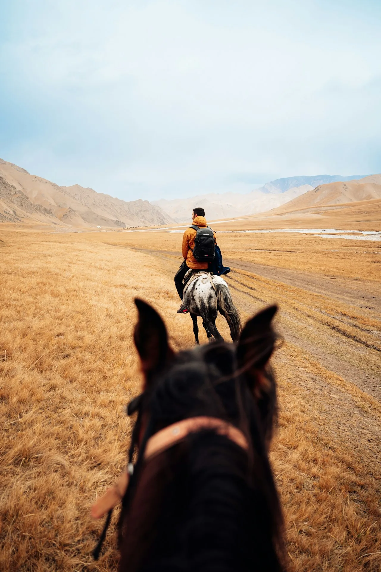 Dos jinetes en un paisaje árido de Kirguistán; foto ilustrativa, no de Merzouga.